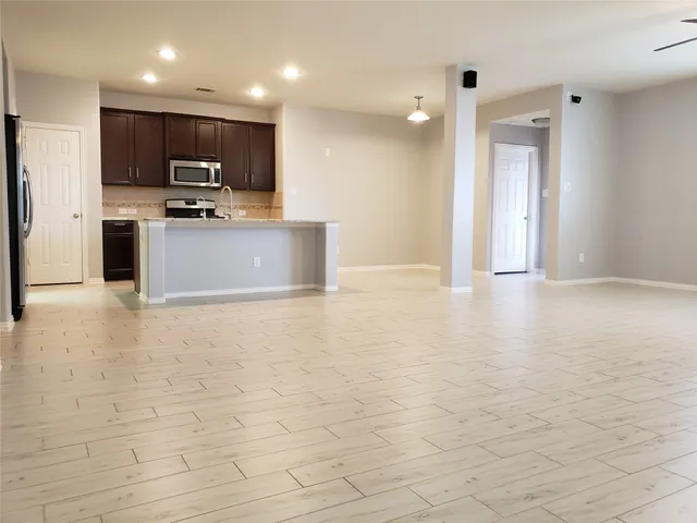 a view of kitchen with stainless steel appliances kitchen island granite countertop a stove a sink a microwave and a refrigerator