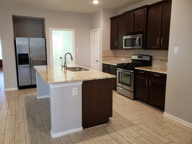 a kitchen with stainless steel appliances granite countertop a stove a sink and a microwave
