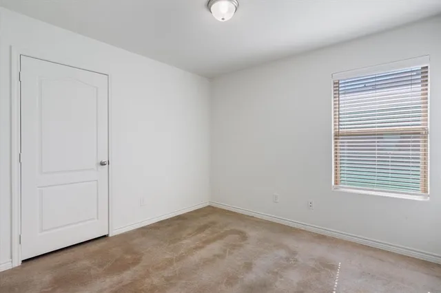 an empty room with chandelier fan and windows
