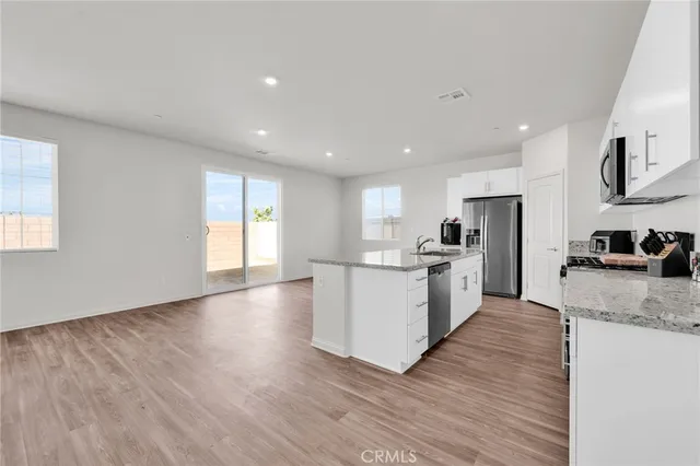 a kitchen with stainless steel appliances granite countertop a white cabinets and wooden floor