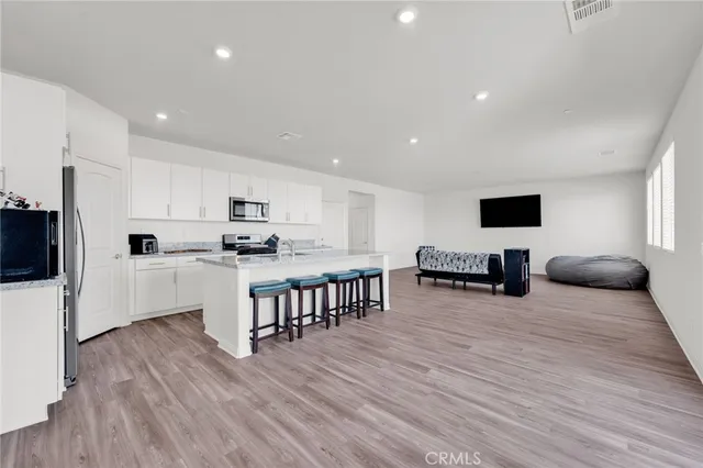 a kitchen with white cabinets stainless steel appliances and wooden floor
