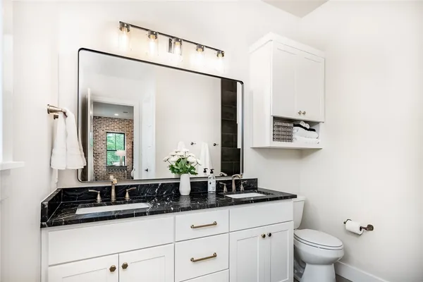 a bathroom with a granite countertop sink a toilet and mirror