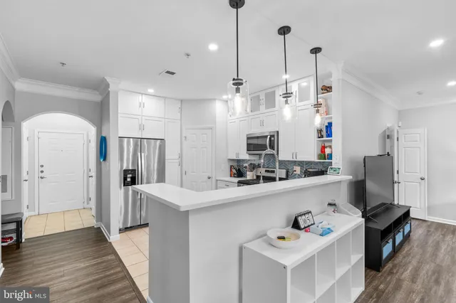 a kitchen with stainless steel appliances a refrigerator a sink dishwasher a oven and a dining table with wooden floor