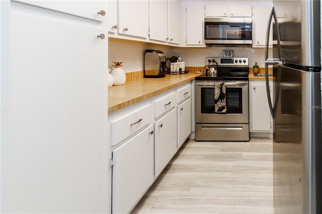 5135 Gemstone Drive, Unit 202 New Port Richey, FL 34652 - Photo 9 of 21 a kitchen with stainless steel appliances granite countertop a stove a microwave and a refrigerator