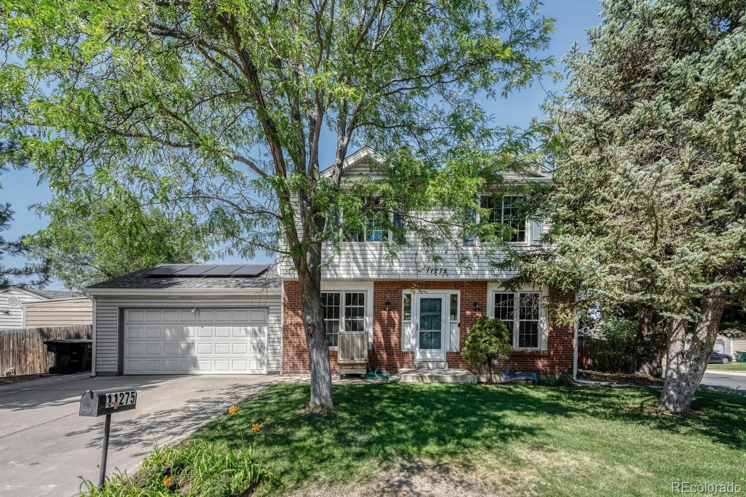 a front view of a house with a garden and trees