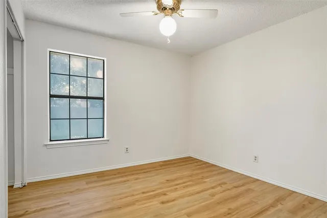 an empty room with wooden floor chandelier and windows
