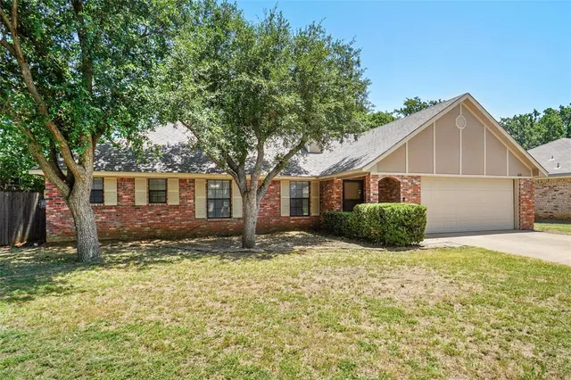 a view of a yard in front of a house with a large tree