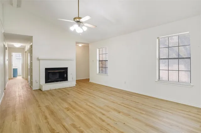 a view of an empty room with wooden floor fireplace and a window