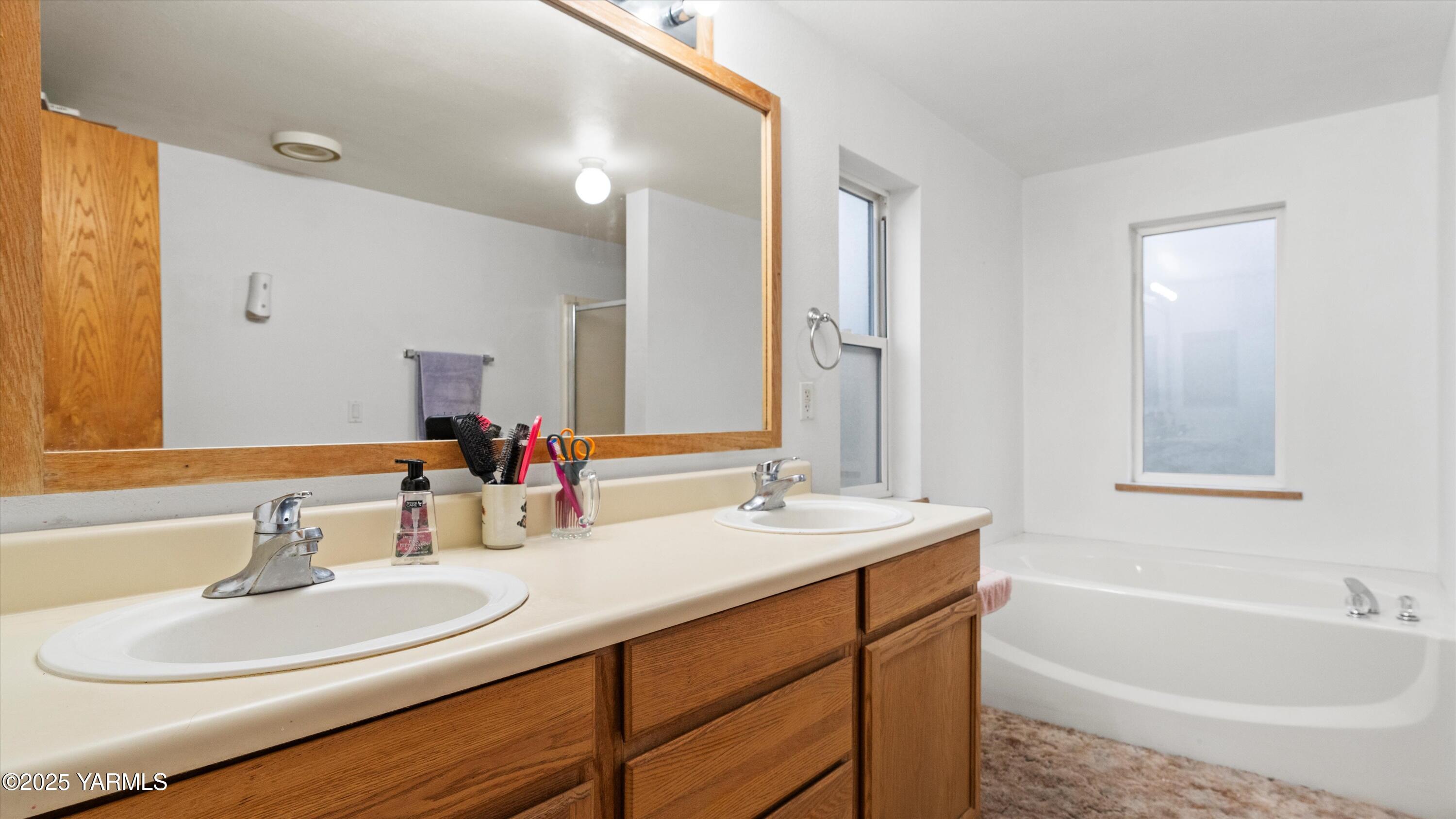 1200 Euclid Street, Unit 76 Grandview, WA 98930 - Photo 21 of 25 a bathroom with a double vanity sink a mirror and a bathtub