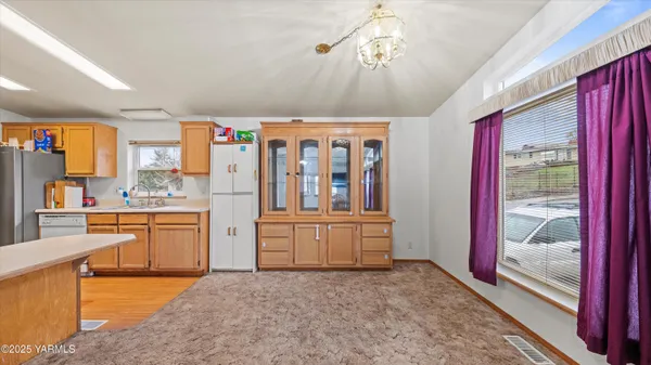 a large kitchen with stainless steel appliances granite countertop a refrigerator a stove a sink dishwasher and wooden cabinets with wooden floor