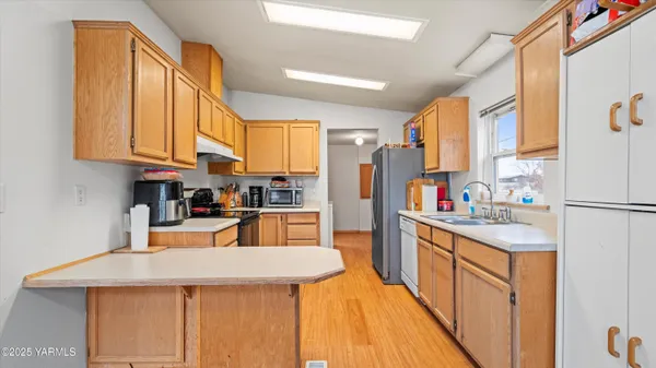 a kitchen with stainless steel appliances kitchen island granite countertop a refrigerator a stove and a sink with cabinets