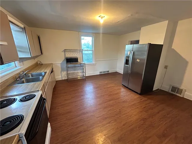 a view of a refrigerator in kitchen and a wooden floor