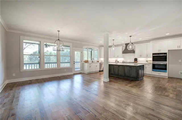 a view of a kitchen with granite countertop a refrigerator oven a sink dishwasher and white cabinets with wooden floor