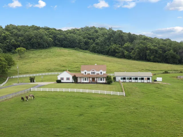 a view of a house with a big yard and large trees