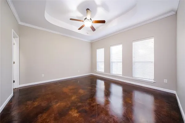 an empty room with wooden floor ceiling fan and windows