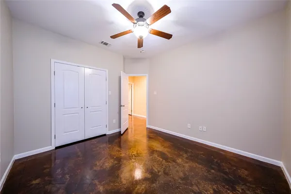 an empty room with closet and a ceiling fan