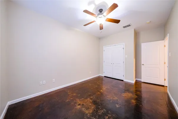 an empty room with wooden floor and a ceiling fan