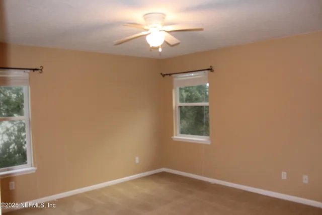 an empty room with windows and fan