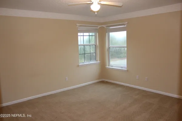 an empty room with windows and fan