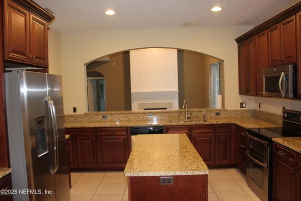 a kitchen with kitchen island granite countertop a sink stove and refrigerator