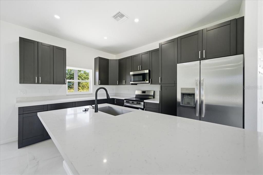 3174 North Sedgewick Road Avon Park, FL 33825 - Photo 3 of 12 a kitchen with a refrigerator a sink a stove a microwave and island