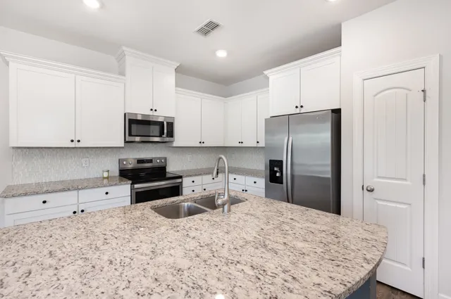 a kitchen with a refrigerator and white cabinets