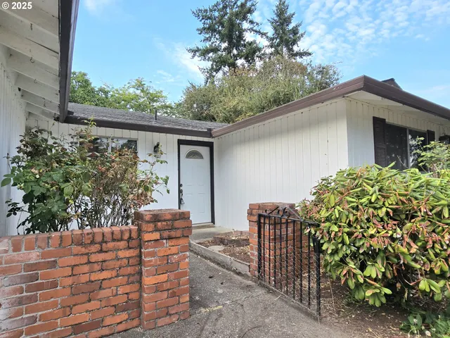 a backyard of a house with large trees and plants