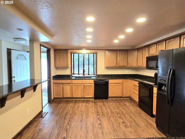 a large kitchen with stainless steel appliances a large counter top a stove and a wooden floors