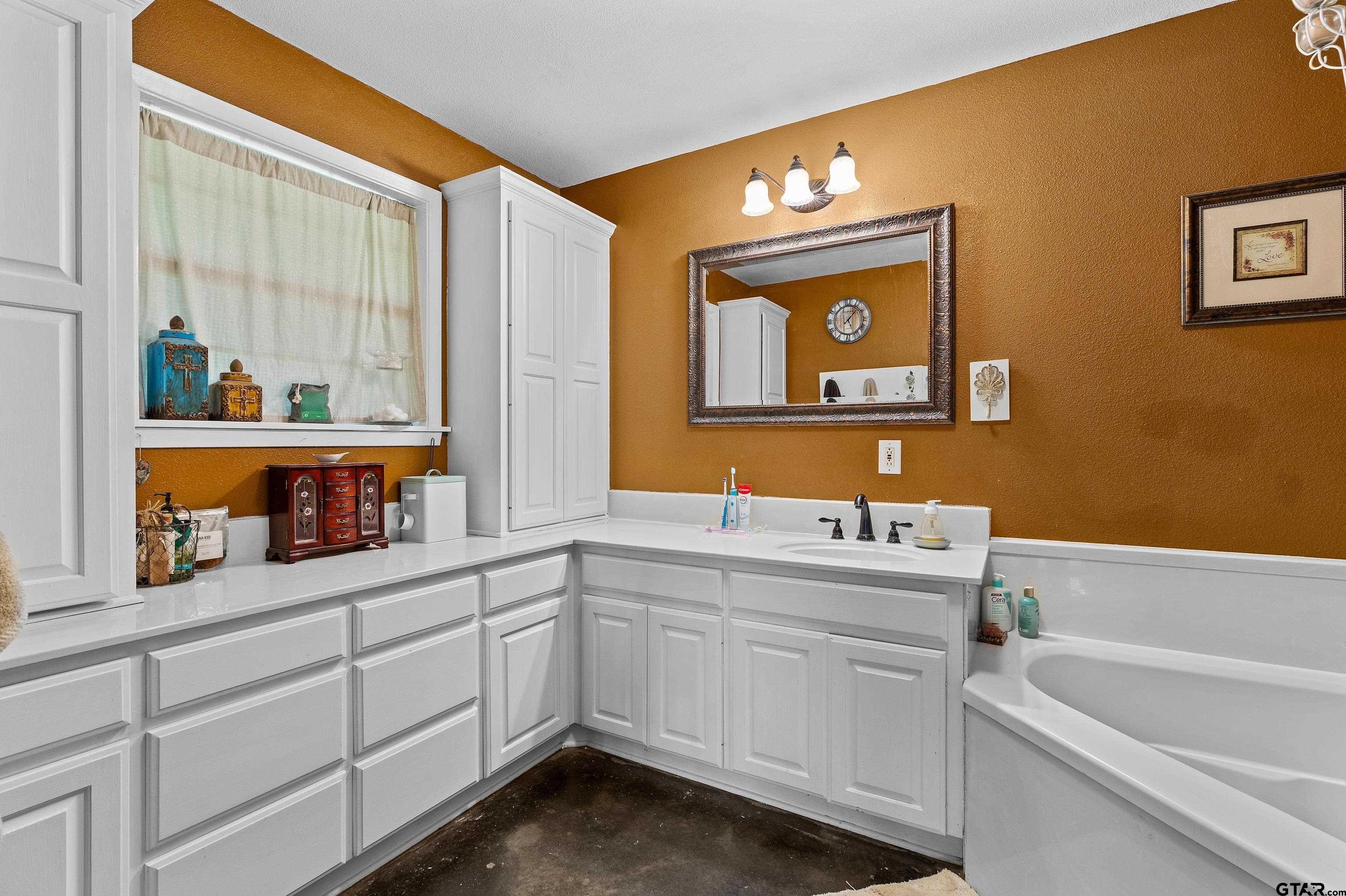 8550 New Hope Road Gilmer, TX 75645 - Photo 11 of 12 a bathroom with a sink a large mirror and a bathtub
