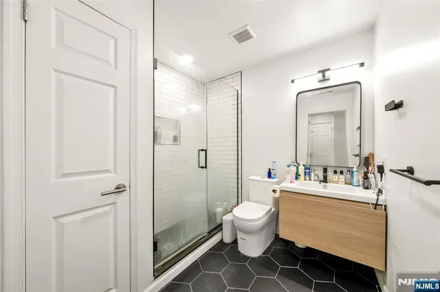 a bathroom with a double vanity sink toilet mirror and shower