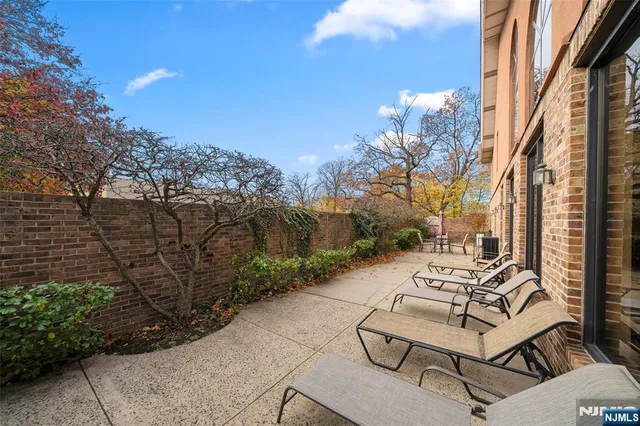 a view of a patio with couches and table and chairs next to yard with wooden fence