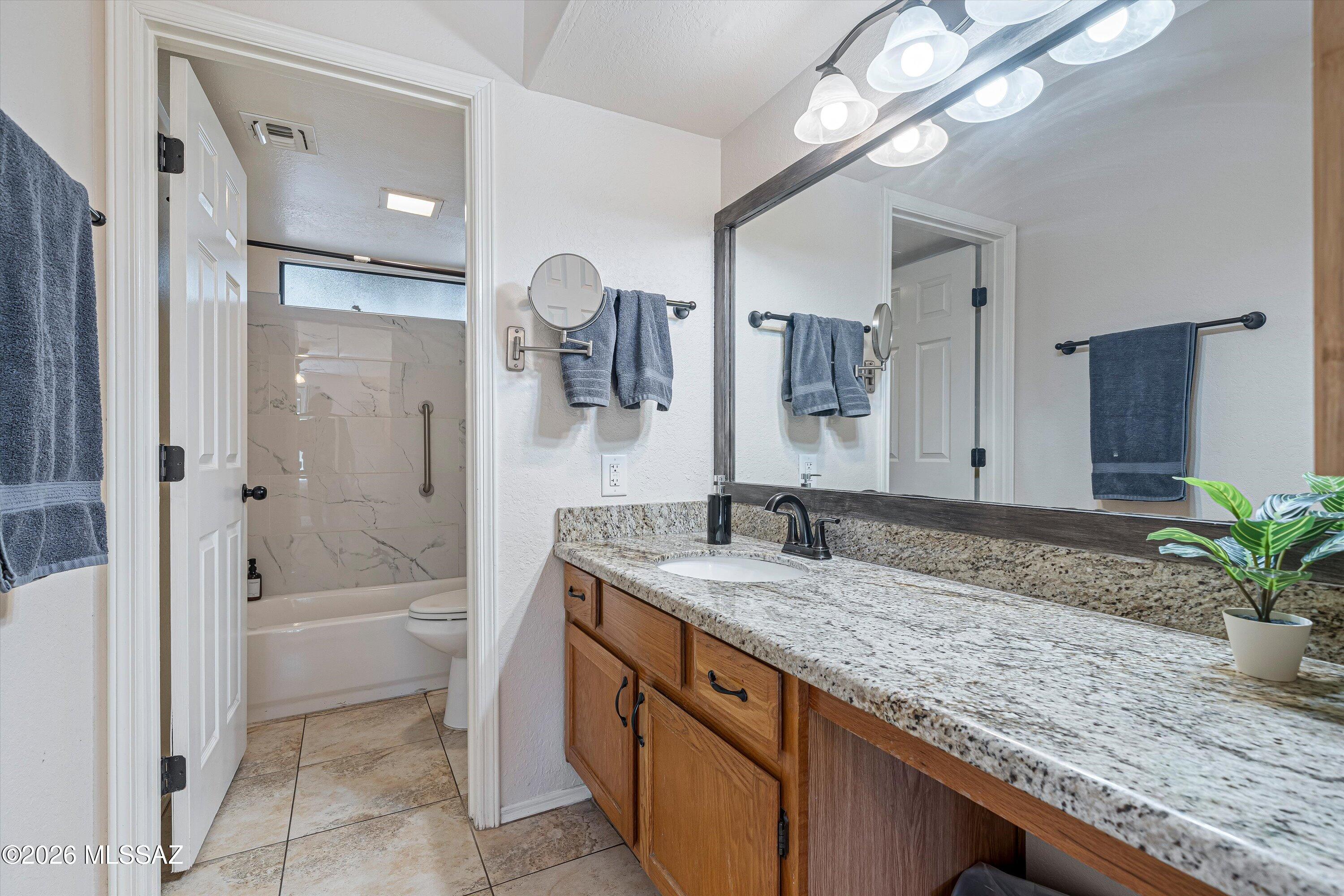 5800 North Kolb Road, Unit 5125 Tucson, AZ 85750 - Photo 15 of 34 a bathroom with a granite countertop sink a mirror a bathtub and shower