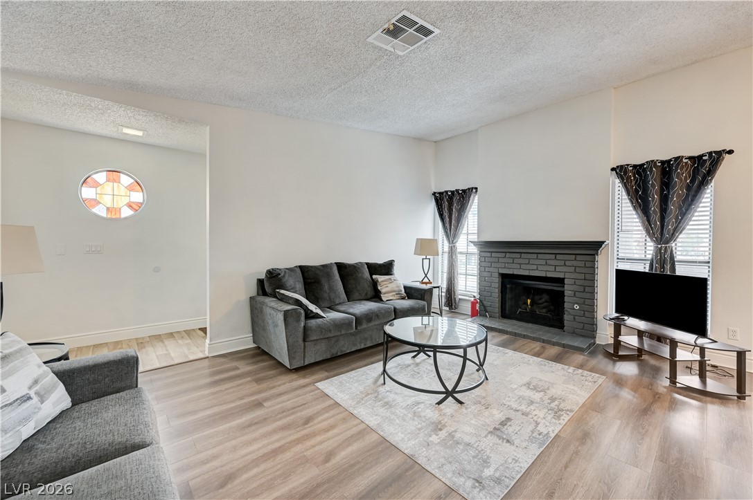 1751 East Reno Avenue, Unit 228 Las Vegas, NV 89119 - Photo 4 of 39 A welcoming living area with rich flooring and a classic fireplace offers warmth and comfort.