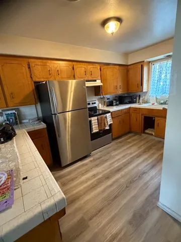 a kitchen with stainless steel appliances wooden floor and a refrigerator