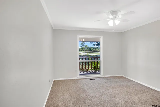 an empty room with windows and chandelier fan