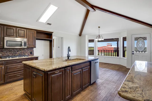 a kitchen with a stove a sink dishwasher oven and a refrigerator with wooden floor