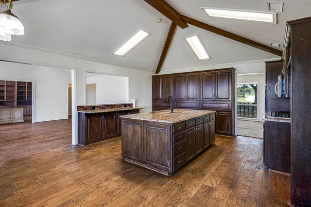 a large kitchen with stainless steel appliances granite countertop a large counter top and a wooden floors