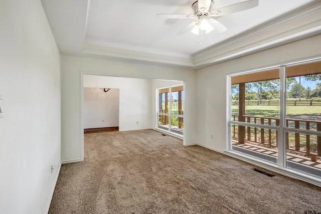 en empty room with windows and ceiling fan