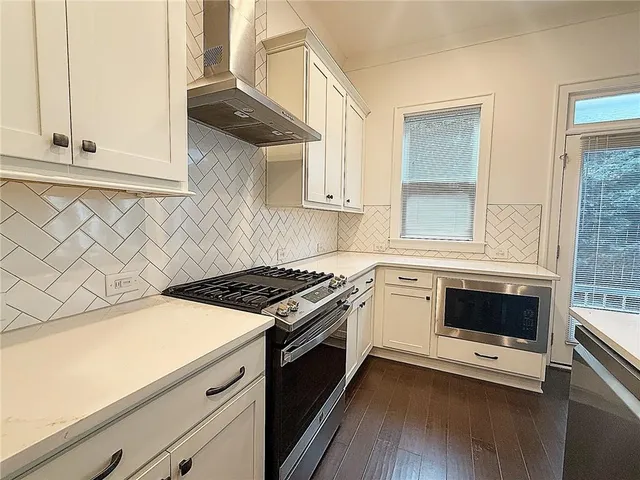 a kitchen with granite countertop a stove and a wooden floor