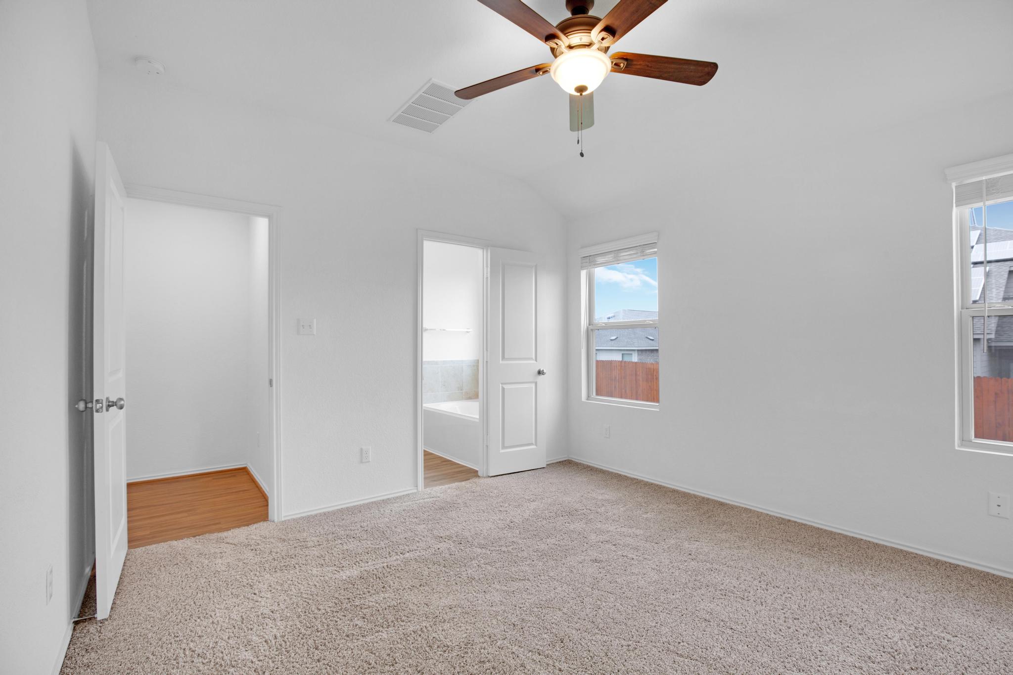 21409 Resource Road Pflugerville, TX 78660 - Photo 11 of 23 Unfurnished bedroom with light carpet, a ceiling fan, vaulted ceiling, and ensuite bathroom