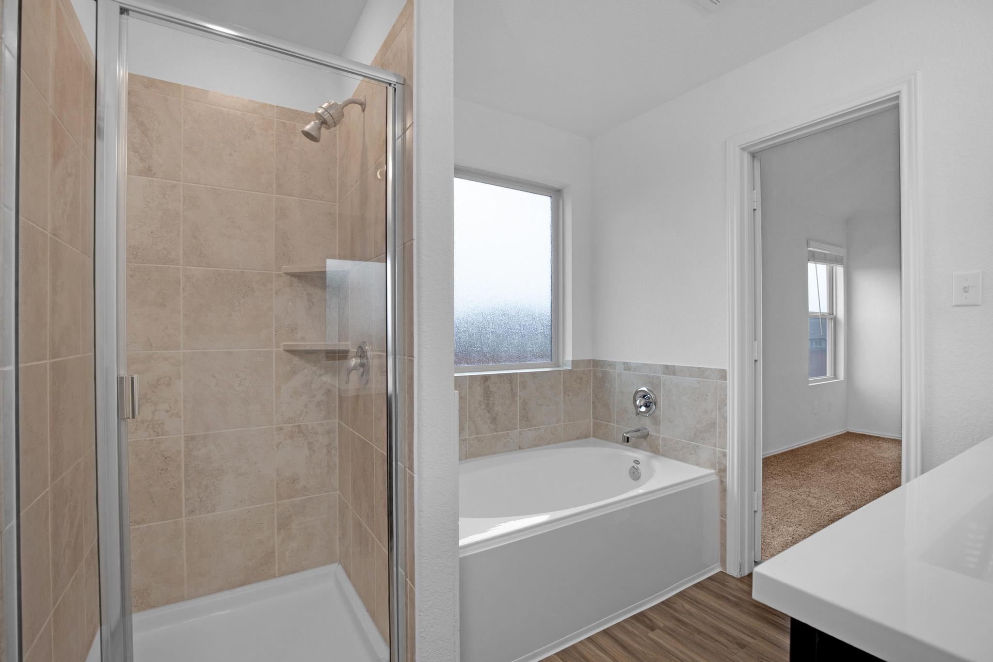 21409 Resource Road Pflugerville, TX 78660 - Photo 13 of 23 Full bathroom featuring vanity, a stall shower, a bath, wood finished floors, and healthy amount of natural light