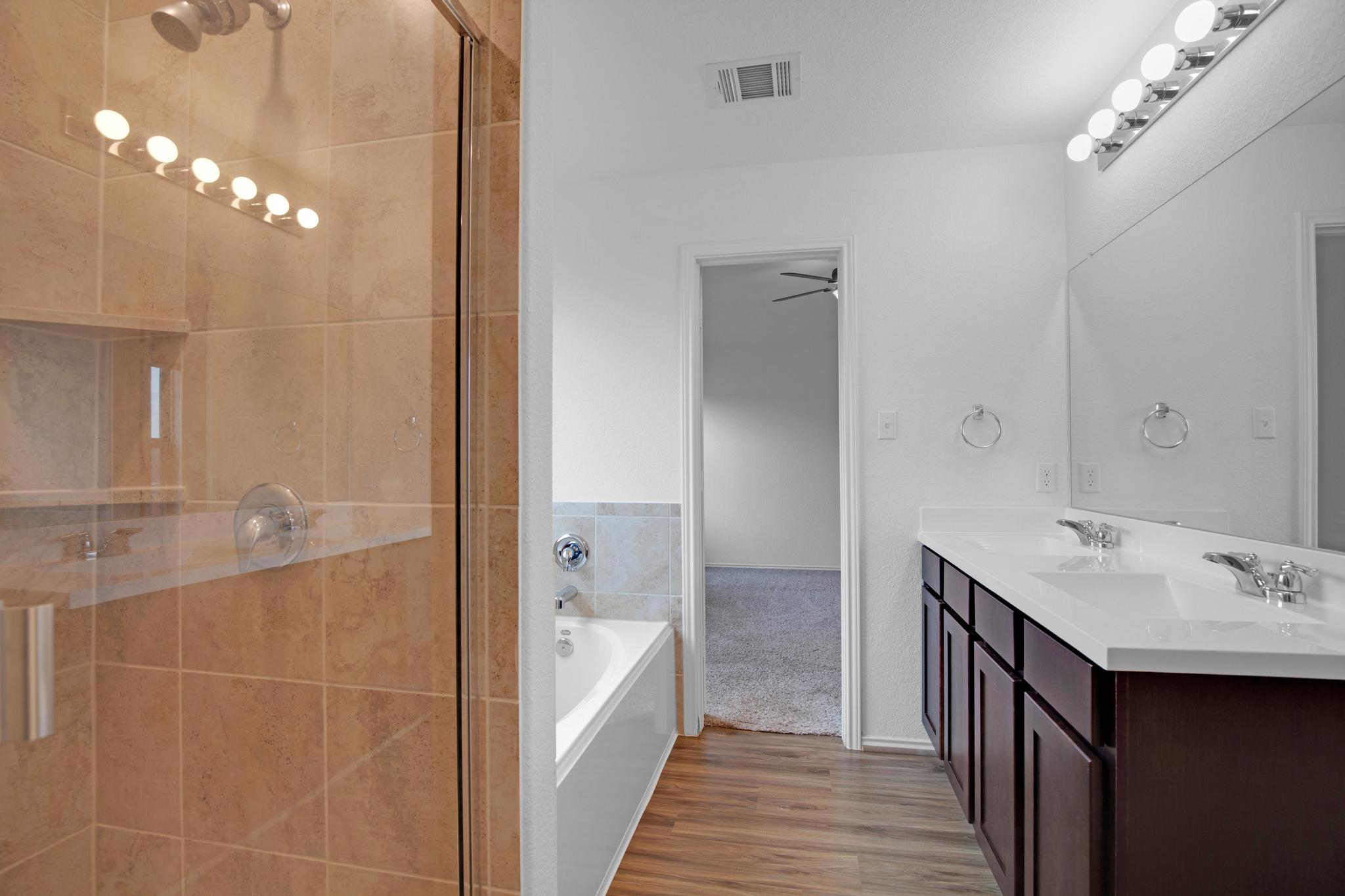 21409 Resource Road Pflugerville, TX 78660 - Photo 15 of 23 Full bathroom featuring double vanity, a bath, a stall shower, and light wood-type flooring