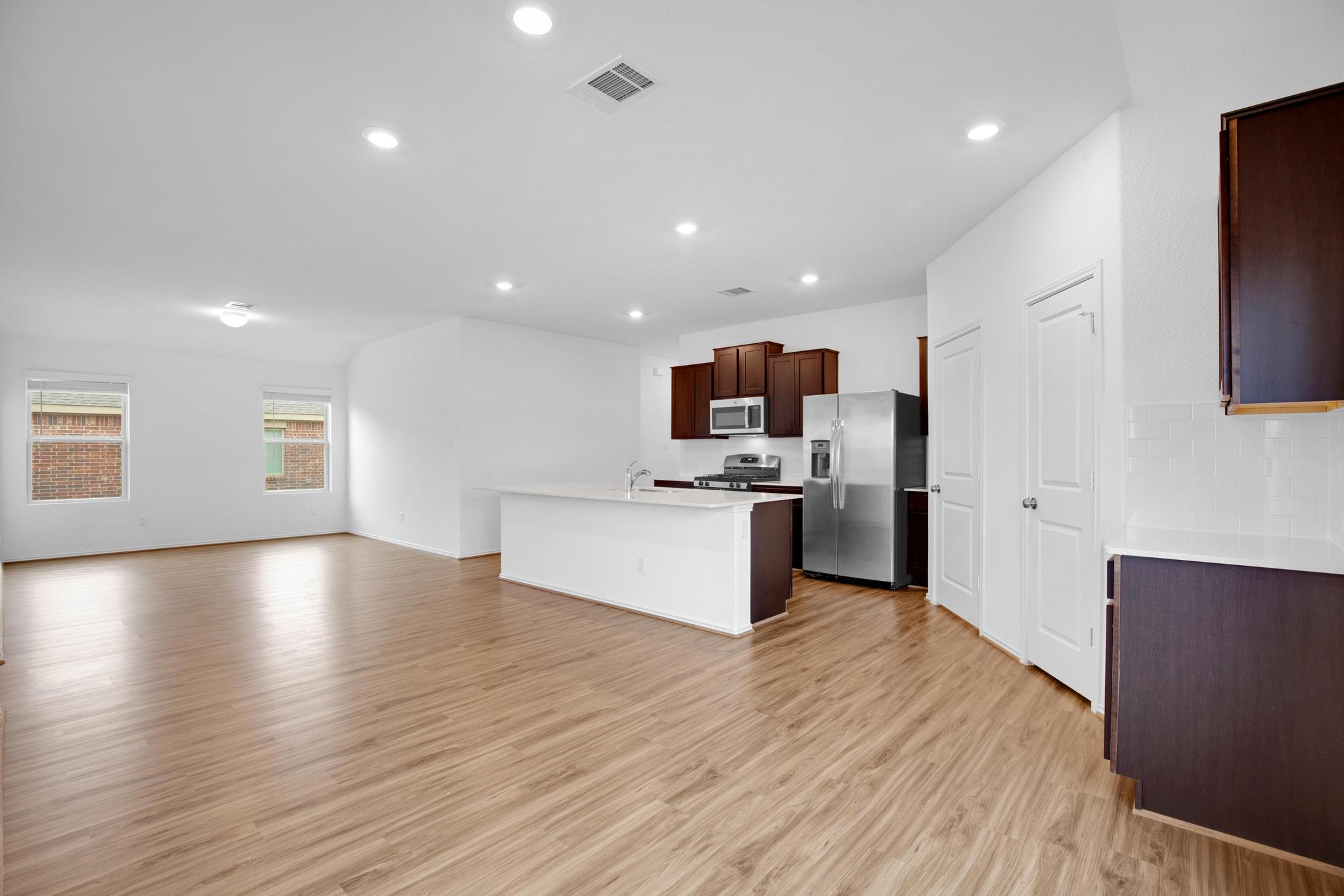 21409 Resource Road Pflugerville, TX 78660 - Photo 23 of 23 Kitchen with stainless steel appliances, open floor plan, light countertops, dark wood finish cabinets, and recessed lighting