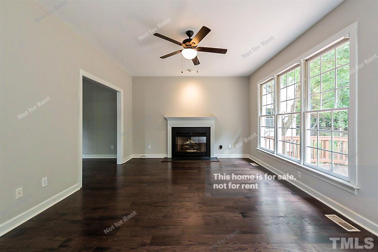 8528 Yucca Trail Raleigh, NC 27615 - Photo 5 of 21 a view of an empty room with wooden floor fireplace and a window