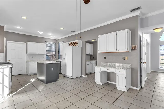 a kitchen with white cabinets and refrigerator