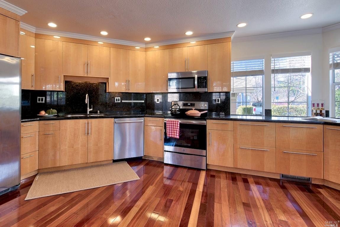 a kitchen with stainless steel appliances kitchen island granite countertop wooden floors and sink