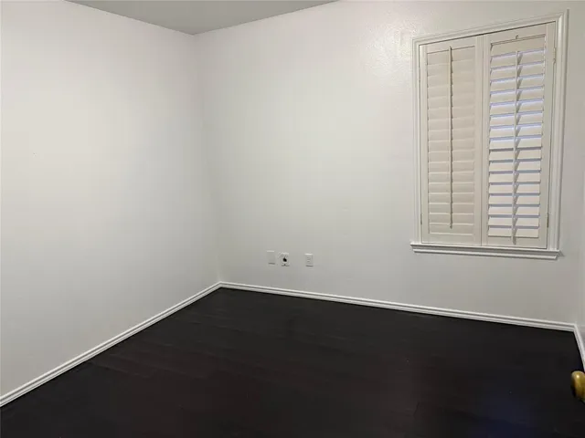 an empty room with windows fireplace and a kitchen view