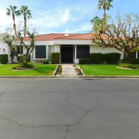 a front view of a house with a yard and potted plants