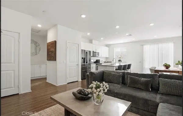 a living room with stainless steel appliances furniture and wooden floor