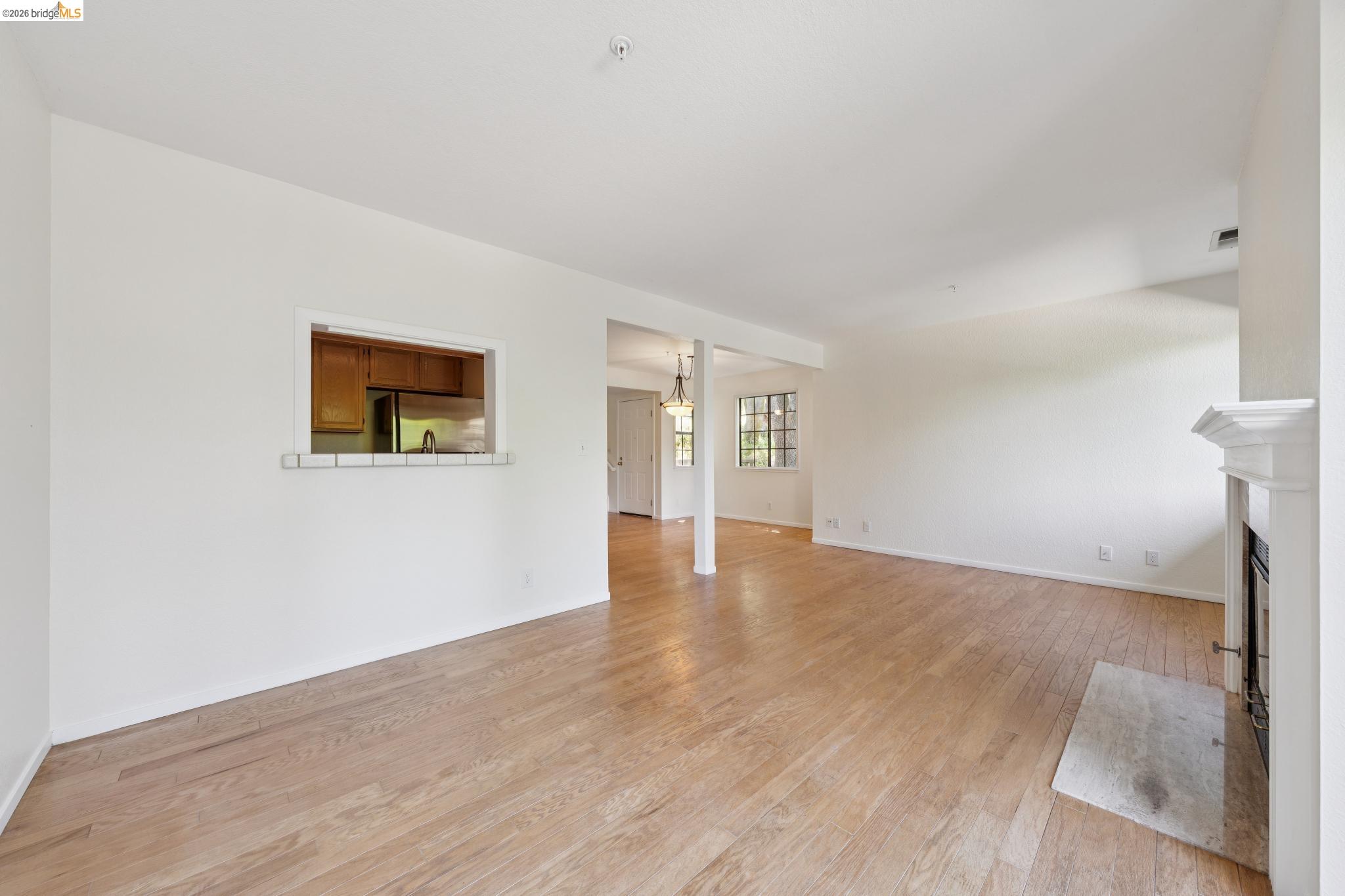 261 Redhawk Road Novato, CA 94949 - Photo 15 of 44 Spacious interior featuring wood-finish flooring, a white-tiled fireplace with a classic mantel, and a pass-through window with a tiled bar-height counter